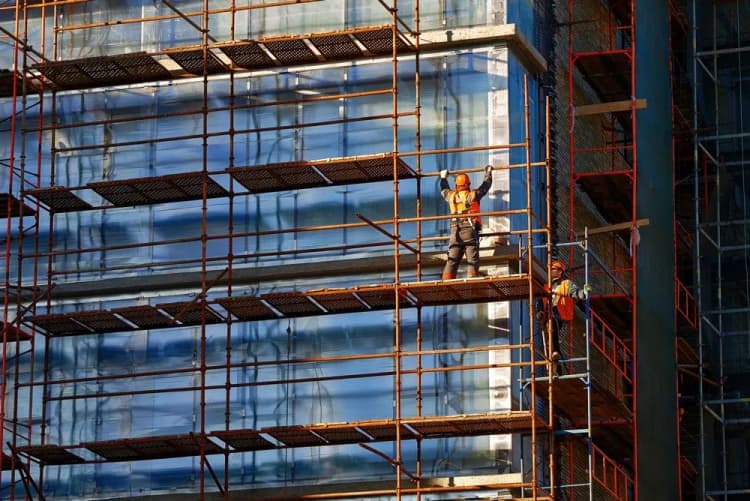 Workers erecting an access scaffold on the face of a glass-clad building